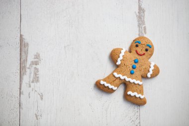 Zencefilli kurabiye şeklinde ahşap masanın üzerinde yatan insan. İyi tadı ile gülümseyen yenilebilir karakter. Makro, parlak beyaz tahta üzerinde kopya alanı kapatın
