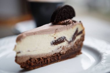 Lezzetli pasta çikolata bisküvi ve kakao çerez parça ile süslenmiş krem ile yemek. Lezzetli ekmek ürün kafede beyaz tabakta servis. Tablo pencerenin öğle yemeği için yakın