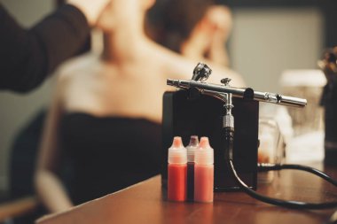 Makyaj airbrush ve boya için makyaj ve arka plan üzerine boyanmış modeli ile visagist masanın üzerinde duran dövme. Solma film renkleri