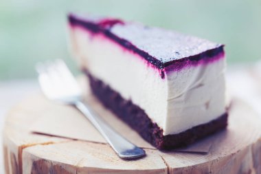 Lezzetli ahududu peynir pastasından bir tahta üzerinde geç bir kafede çatal ile görev yaptı. Lezzetli pasta - krem, çilek ve taze bisküvi. Makro fotoğraf kadar kapatın.