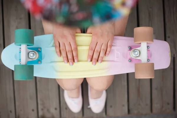 拿着五颜六色的短巡洋舰滑板的年轻女孩 流行的小滑板甲板 时尚的装备 从上面拍摄 专注于模型的手 — 图库照片