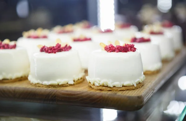 Delicious little white cupcakes with raspberries stored in cafe refrigerator.Itailan restaurant menu food