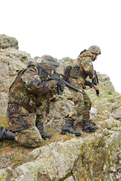 Military assistance.Army teamwork.Armed soldiers in camouflage of Ukrainian army in combat uniform.Soldier helps team member climb rock outdoor.War in Eastern Ukraine.Heavy ammunition,automatic rifle