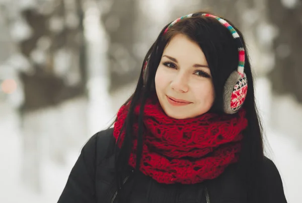 かわいい若いの白人の女の子は彼女の首に暖かい冬コート 赤いスカーフで頭に面白いカラフルなイヤーマフ屋外ポーズします 笑顔の女性モデル — ストック写真
