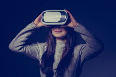 Sanal gerçeklik ile oynayan genç esmer kız portresi stüdyo mobil oyun uygulama için koruyucu gözlük. Kız mobil oyunlar apps ile yenilikçi 3d vr kulaklık kullanın. Trendy artar gerçeklik aygıtı kullanımda