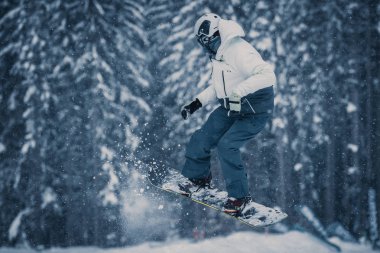 BUKOVEL, UKRAINE - 20 MARCH, 2018: Snowboard contest in winter park. Young athletes compete in snowboarding. Cool extreme sport competition for youth. clipart