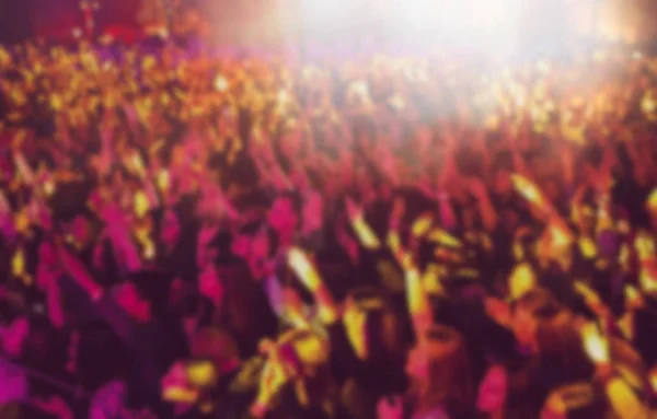 Vibrant pop music concert background.Big group of happy young people partying on musical festival in night club.Colorful abstract back ground for nightclub party poster.Fans hands and bright lights