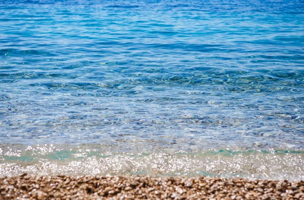 美しい小石の海岸と深い青色の海 クリスタル クリアなアドリア海の波ビーチでローリングします 夏休みの旅行先 観光テーマの壁紙 海でダイビングをお楽しみください — ストック写真