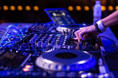 Party dj kız müzik koyu mavi ışık sahnede profesyonel ses ekipmanları Kur ile karışımları. Kadın dj mix popüler parçaları ile gece kulübünde çalıyor. Ses geçişi ayar düğmesi topuzu çapraz ses mikseri yandan DJs