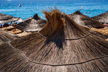 Bungalow with palm tree leaves on roof on the beach of Adriatic Sea in Croatian Riviera resort in summer