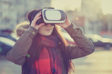 Mobil oyun uygulamaları için modern sanal gerçeklik gözlüklü oynayan genç kız. Mobil apps ile yenilikçi 3d kulaklık kullanın. Fütüristik artar gerçeklik oyun Gadget'ı. Kadın oyun vr başlı takım