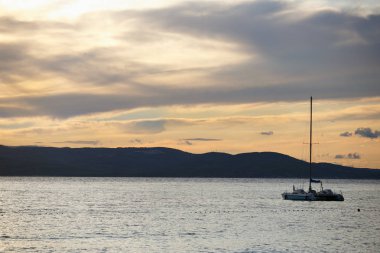 Adriyatik Denizi günbatımında sürüklenen küçük kiralama yat. Gezisi bir motorlu tekne doe yaz tatil kira. Croatia.Dramatic gün batımı aydınlatma arka plan üzerinde doğal güzelliği yakalayın. Gece karanlığında dalış gitmek