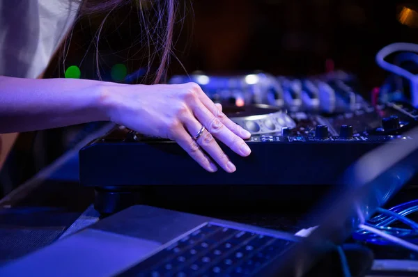 Female dj plays music on stage with digital cd player turn table.Professional audio equipment for disc jockey on concert scene.Djs hand on turntables play button