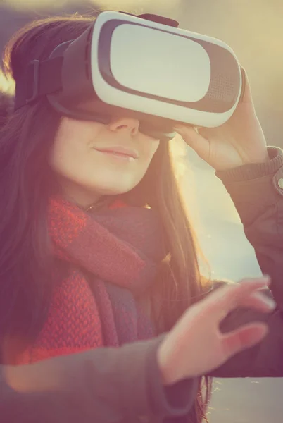 若い女の子使用クールな新しい拡張現実メガネ冬の日没で屋外モバイル ゲーム用 革新的な ヘッドセットと携帯ゲームのアプリを使用します 最新のバーチャルリアリティ ゲーマーのガジェット — ストック写真