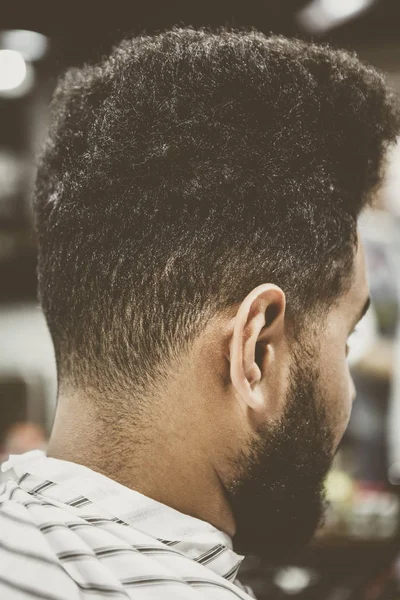 Nape and neck of young black man in barbershop.African guy cuts his hair and trim beard in barber shop.Male beauty treatment process in hairdresser salon.