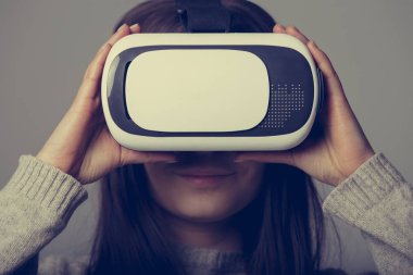 Genç ve güzel kadın için mobil oyun uygulamalar yeni sanal gerçeklik gözlükle stüdyo portre. Kız mobil oyunlar apps ile yenilikçi 3d vr kulaklık kullanın. Trendy artar gerçeklik aygıtı kullanımda