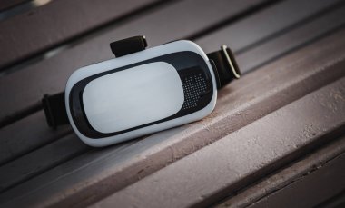 Mobil oyun app akıllı telefon oynamak için Modern artar gerçeklik Vr gözlük parkta bankta yatıyordu. Portatif Oyun Kulaklığı aygıt için smartphone. Video oyun üstünde belgili tanımlık gitmek. Popüler yeni oyun becerikli alet