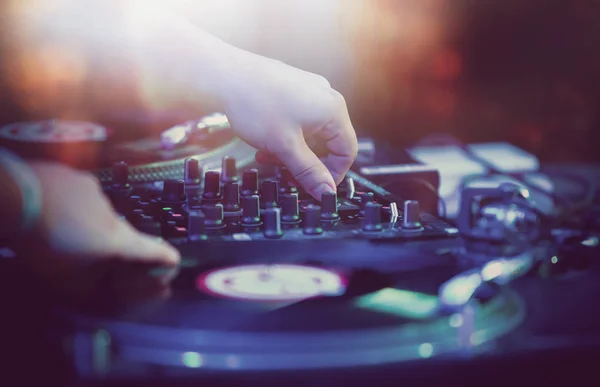 Hip hop concert dj plays set on night club stage in bright lights.Hands of disc jockey on vinyl record player and sound mixer panel.Musician playing rap music on festival in nightclub