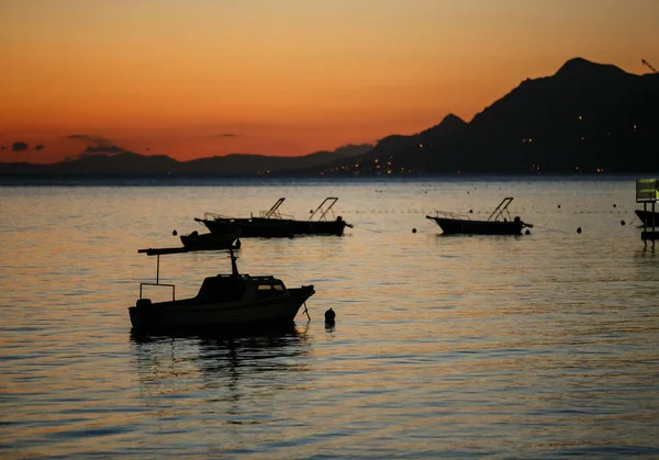 Silhouette of small fishing motor boats and rental yachts drifting in calm  Adriatic Sea at sunset in Croatia.Beautiful nature at dusk.Travel  destination for summer vacation tour.Rent boat for cruise - Stock Image 