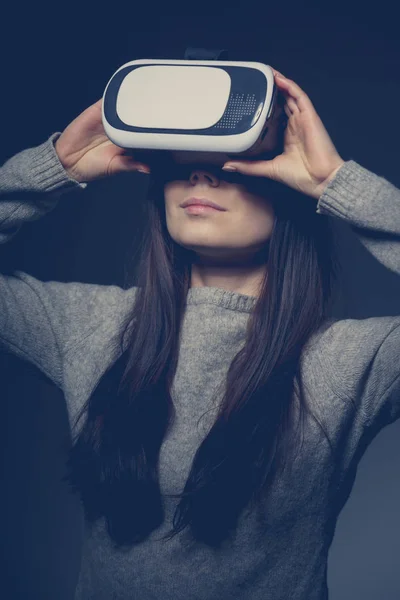 Studio portrait of young white girl enjoying new virtual reality glasses for mobile games apps.Girl use mobile game application with innovative 3d vr headset.Trendy augmented reality gadget play