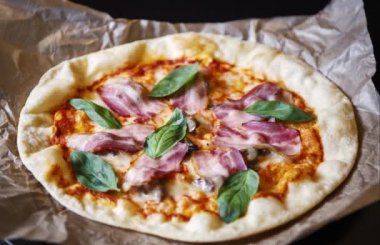 Italyan kafede lezzetli pizza. Italya 'da gelenek yemek görüntüleri, Yeşil fesleğen yaprakları, siyah zeytin, yanmış peynir ve pastırma dilim ile pişmiş hamur tabanı.