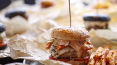 Lezzetli büyük şişman duble hamburgerin görüntüleri. Amerikan Fast food restoran menü çanak. Sos ile ızgara büyük Burger, domuz ve yakıcı peynir kafede kahverengi kağıt üzerinde hizmet vermiştir. Hızlı yiyecek video yakın çekim.