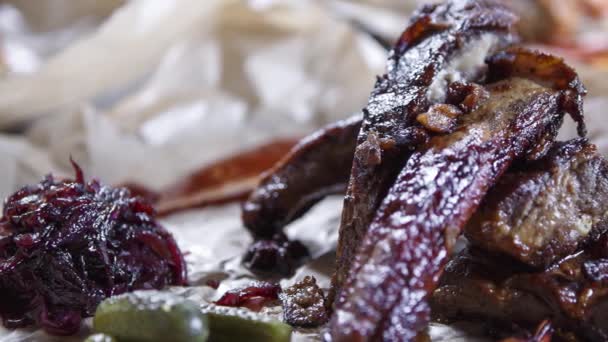 野菜と装飾的な細工された茶色の紙に提供される焼き豚のリブの映像 スモークバーベキューステーキリブ レストランのメニューで骨に焼き肉のビデオ 脂肪と不健康な食べ物 — ストック動画