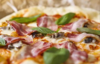 Italyan kafede lezzetli pizza. Italya 'da gelenek yemek görüntüleri, Yeşil fesleğen yaprakları, siyah zeytin, yanmış peynir ve pastırma dilim ile pişmiş hamur tabanı.