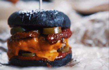 Lezzetli büyük şişman duble hamburgerin görüntüleri. Amerikan Fast food restoran menü çanak. Sos ile ızgara büyük Burger, domuz ve yakıcı peynir kafede kahverengi kağıt üzerinde hizmet vermiştir. Hızlı yiyecek video yakın çekim.