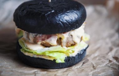 Lezzetli büyük şişman duble hamburgerin görüntüleri. Amerikan Fast food restoran menü çanak. Sos ile ızgara büyük Burger, domuz ve yakıcı peynir kafede kahverengi kağıt üzerinde hizmet vermiştir. Hızlı yiyecek video yakın çekim.