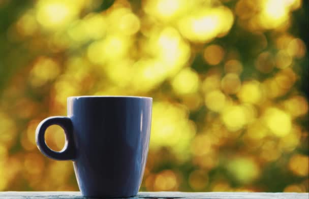 朝の窓枠に紫色のコーヒーマグの映像 一日を始めるために芳香族エネルギッシュな飲み物を味わいます 背景に緑の公園の木 — ストック動画