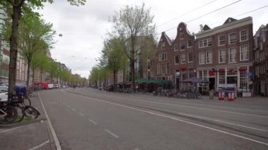 AMSTERDAM, NETHERLANDS - 27 Nisan 2019: Amsterdam 'ın merkezinde tramvay rayları ve bisiklet parkı olan şehir caddesi
