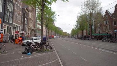AMSTERDAM, NETHERLANDS - 27 Nisan 2019: Amsterdam 'ın merkezinde tramvay rayları ve bisiklet parkı olan şehir caddesi