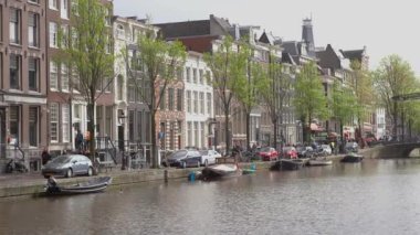 AMSTERDAM, NETHERLANDS - 27 NİSAN, 2019: Amstel nehrinde botlar ve Amsterdam şehrinin merkezinde kanal üzerinde köprüler. Hollanda 'da güzel, eski Hollandalı evler  