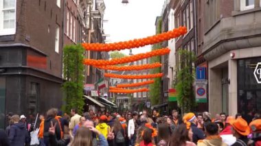 AMSTERDAM, NETHERLANDS - 28 Nisan 2019: Amsterdam 'ın merkezinde insanlar her yıl düzenlenen Kral Günü' nü (Flaman: Koningsdag) kutluyorlar. Hollanda Krallığı 'nın popüler ulusal bayramı. Eski kentte yürüyen turistler 