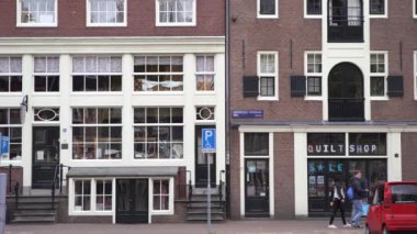 AMSTERDAM, NETHERLANDS - 27 Nisan, 2019: Amsterdam 'ın eski şehir merkezi. Geleneksel Hollanda mimarisi. İnsanlar sokakta yürüyor, Hollanda 'da bisiklet sürüyor. Güzel evler