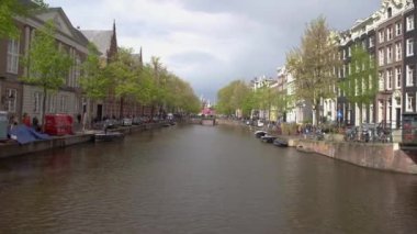 AMSTERDAM, NETHERLANDS - 27 NİSAN, 2019: Amstel nehrinde botlar ve Amsterdam şehrinin merkezinde kanal üzerinde köprüler. Hollanda 'da güzel, eski Hollandalı evler  