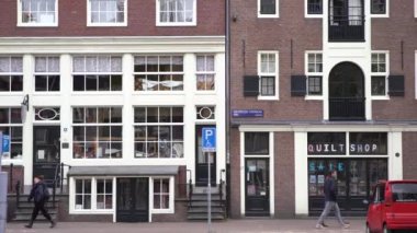 AMSTERDAM, NETHERLANDS - 27 Nisan, 2019: Amsterdam 'ın eski şehir merkezi. Geleneksel Hollanda mimarisi. İnsanlar sokakta yürüyor, Hollanda 'da bisiklete biniyorlar. Güzel evler
