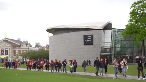 纽德兰 Amsterdam 2019年4月27日 一群游客在阿姆斯特丹市中心的Museumplein走过文森特 凡高博物馆 欧洲文化旅游的热门旅游胜地 — 图库视频影像