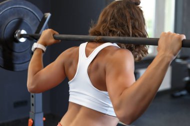 Spor kulübünde omuzlarında barbell ile genç beyaz kadın eğitim