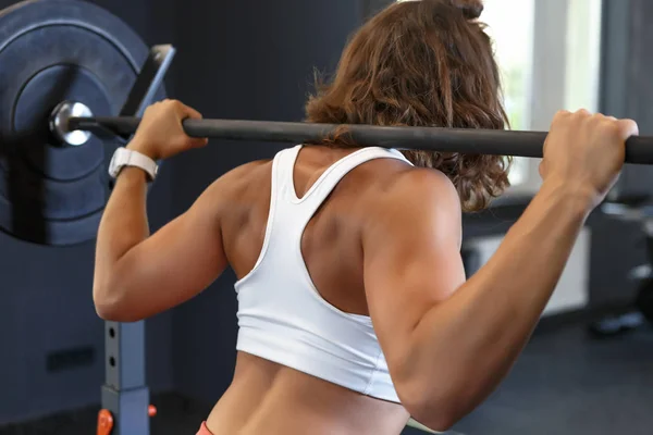 Joven mujer blanca entrenando con barra en sus hombros en el club de gimnasia — Foto de Stock