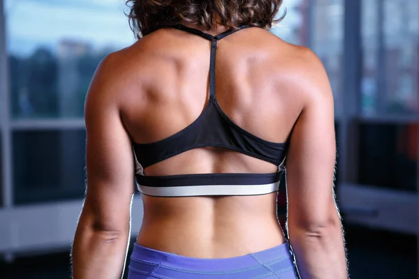 Chica joven fuerte con los músculos de la espalda bombeada posando en el club de gimnasia — Foto de Stock