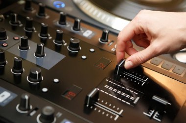 Kadın dj gece kulübünde sahnede profesyonel ses ekipmanları ile müzik çalar. Hip hop disk jokey kız üst ses karıştırıcı paneli ile müzikal parça karıştırır. Dj'lerin el ayarhacmi fader odaklanın 