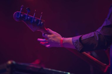 Bas gitarist müzik salonunda rock konser sahnesinde solo rol oynuyor. Profesyonel müzisyen yaylı çalgılar üzerine çalıyor. Gitar headstock ve odak tuşu tuşları. Kulüpte Heavy metal müzik festivali