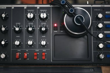 Ses kayıt stüdyosunda profesyonel synth tahtası ve stereo kulaklıklar. Müzik üretimi için yüksek kaliteli analog ses ekipmanları. Retro analog synthesizer güverte ve büyük kafa telefon seti