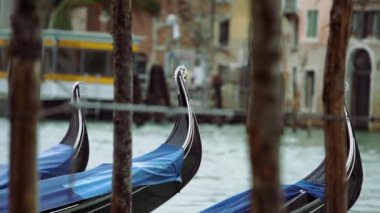 Traditional Venetian gondola boats tied on pier in Grand Canal near Rialto Bridge in bad weather.Rainy day in Venezia,popular tourist destination in Italy