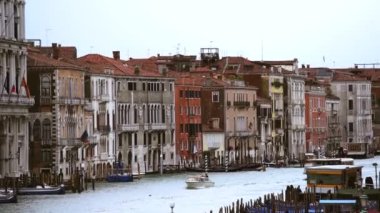 VENICE,ITALY-4 MAY,2019:Motor boat in Grand Canal shot from Rialto Bridge in Venice.The most popular tourist place in Venezia.Old Italian houses and gondola boats drifting on waves in rainy spring day