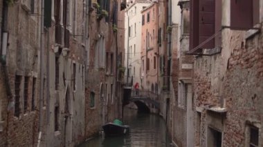 VENICE,ITALY-4 May,2019:Backstreet of Venezia.Small boat drifting in canal between ancient venetian houses.Traditional narrow street of Venice in Italy,popular tourist destination for cultural tourism