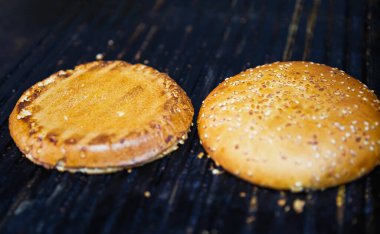 Hamburgerler için fast food restoranının mutfağında ızgara yapan kızarmış çörekler.