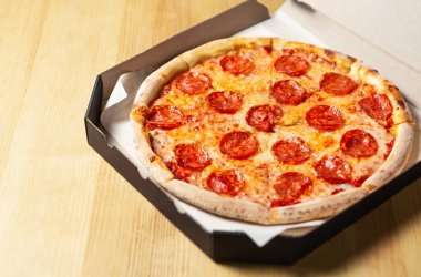 Pepperoni pizza teslimatı. Pizzacıdan karton kutuda paketlenmiş fast food teslimatı. Pepperoni füme sosisli fırında pişirilmiş lezzetli İtalyan yemeği, öğle yemeği için hamurlu hamur tabanında mozarella peyniri.